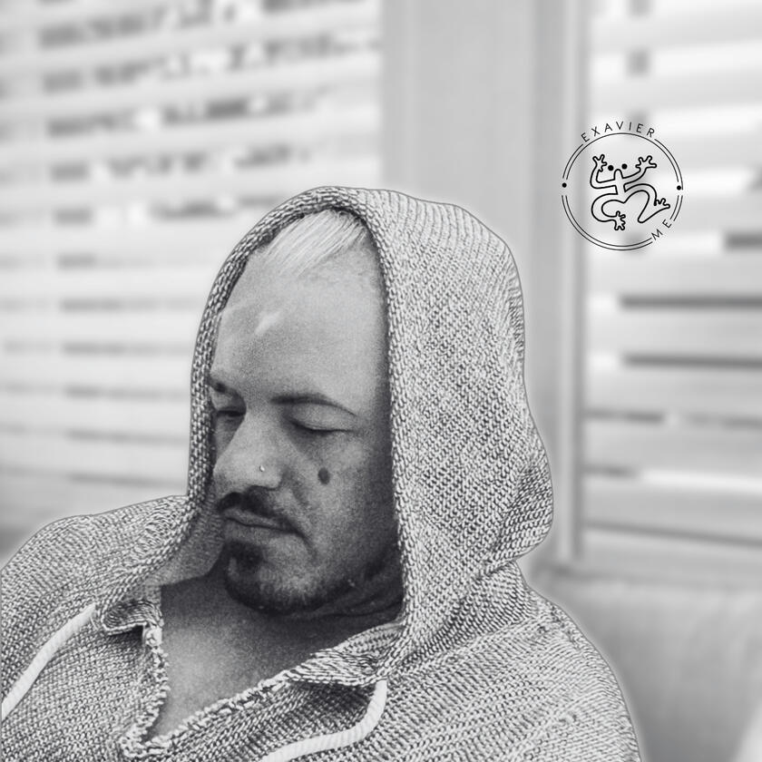 Exavier.Me Gallery Image 4 Black & White photo of Exavier Me sitting looking down while a hoody covers the back part of his head.